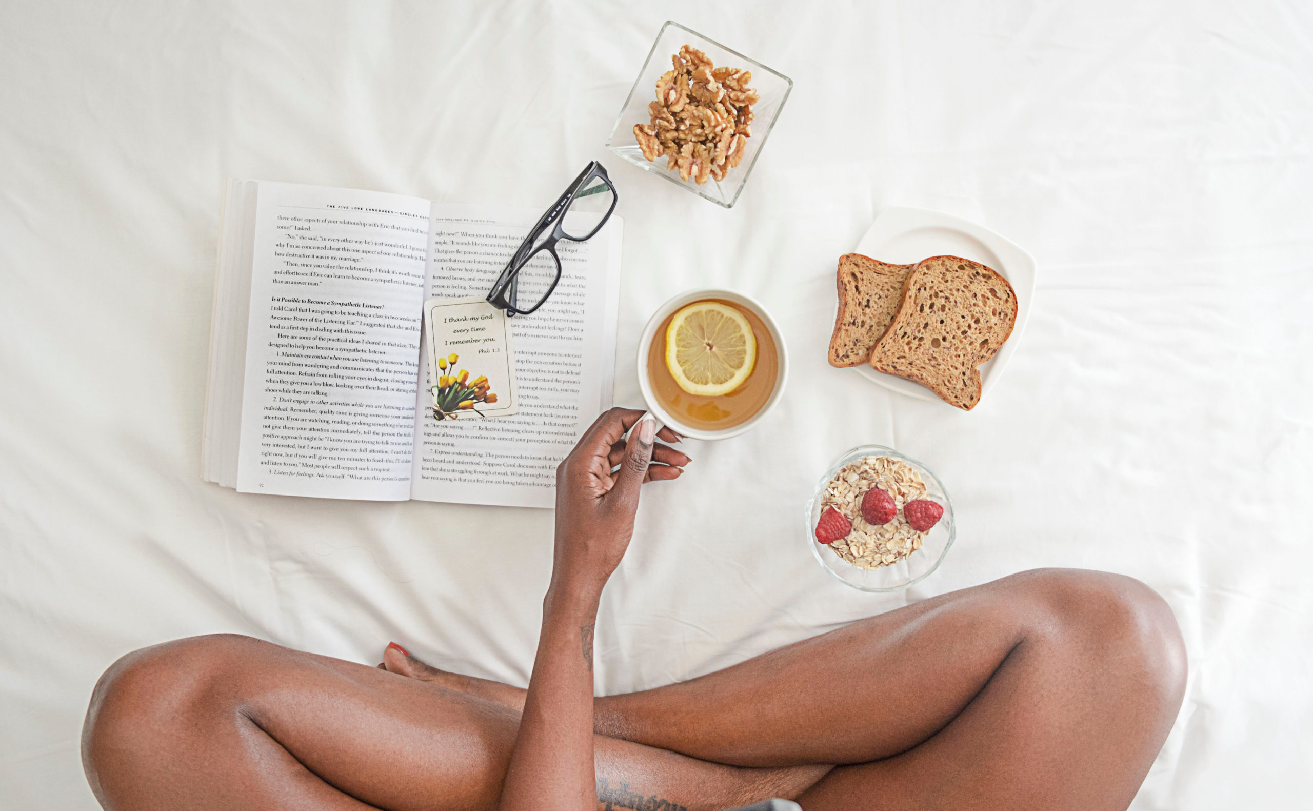 Canva – Person Holding White Ceramic Mug With Lemon Near Book and Sliced Bread on White Comforter